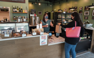 Photo of woman handing a cup of coffee to a customer at La Cocina VA's community cafe